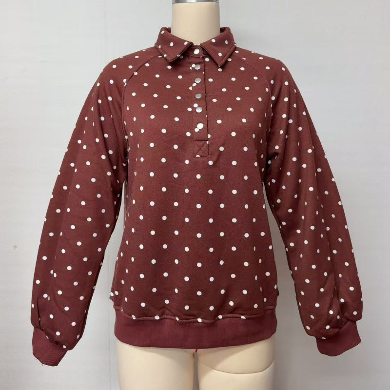 A long-sleeve collared pullover top in a rust brown color with white polka dots, displayed on a beige dress form mannequin against a plain white wall.