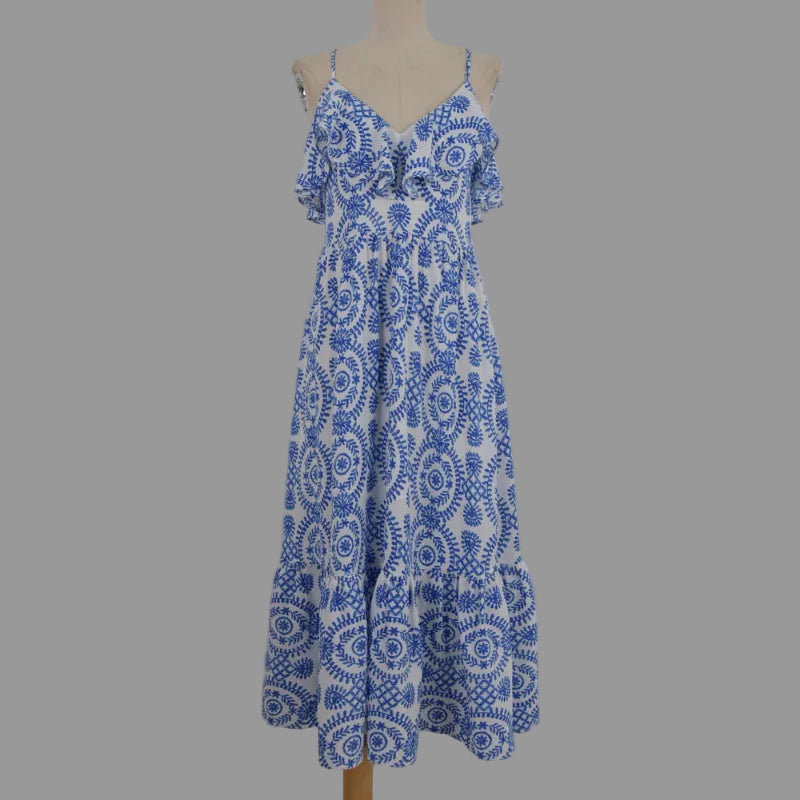 A blue and white patterned maxi dress with thin shoulder straps and a ruffled bodice, displayed on a beige dress form against a plain light gray background.