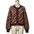 A cropped cardigan sweater displayed on a cream mannequin torso. The cardigan features a geometric plaid pattern in olive green, burgundy, and light pink, with solid burgundy ribbed trim on the collar, cuffs, and hem, and matching burgundy buttons down the center front.