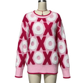 A pink and magenta knit sweater with a 3D 'X' and 'O' pattern, displayed on a mannequin against a neutral gray background.