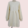 An off-white quilted long-sleeve dress displayed on a mannequin against a plain light gray background.