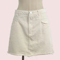 A light beige denim mini skirt with a raw, frayed hem, displayed on a cream-colored dress form mannequin against a plain light gray background.