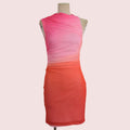 A sleeveless draped dress on a mannequin, featuring a color-blocked design with a bright pink and orange gradient.