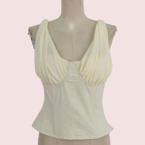 A pale yellow sleeveless top with a sweetheart neckline and gathered bust detail, displayed on a beige mannequin torso against a solid light pink background.
