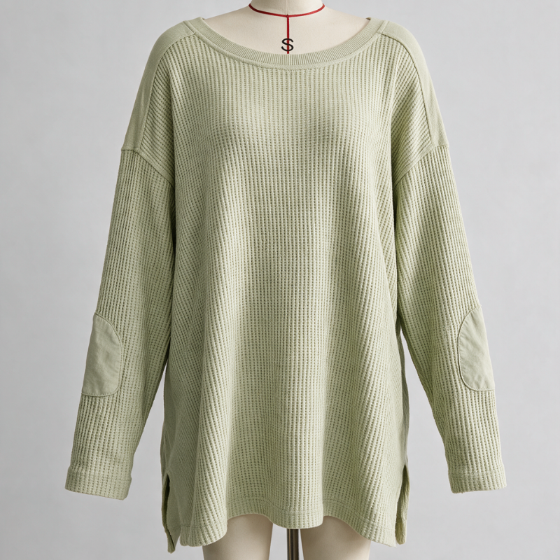 A light sage green ribbed knit sweater with elbow patches and a wide boat neckline, displayed on a cream dress form mannequin against a neutral gray background.