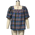 A plaid puff-sleeve top displayed on a cream mannequin torso against a plain light gray wall. The top has a square neckline, smocked upper chest, and a multicolor tartan pattern with blue, purple, green, and red tones.