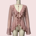 A pink long-sleeve blouse with layered ruffles, a deep V-neckline, and front tie details, displayed on a cream mannequin against a plain light gray background.