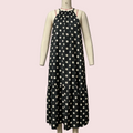 A sleeveless black midi dress with a white polka dot pattern displayed on a cream-colored mannequin. The dress features a gathered halter-style neckline with thin red shoulder straps and a tiered skirt.