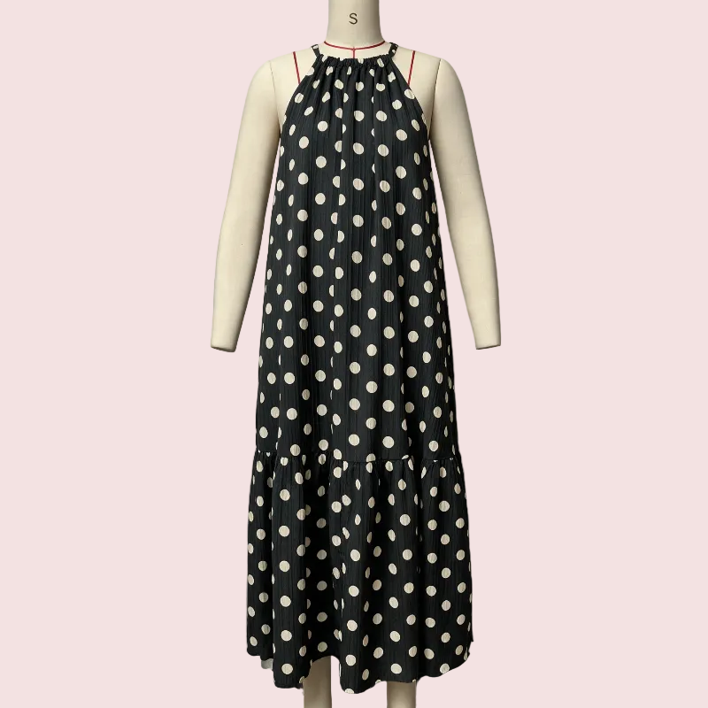 A sleeveless black midi dress with a white polka dot pattern displayed on a cream-colored mannequin. The dress features a gathered halter-style neckline with thin red shoulder straps and a tiered skirt.