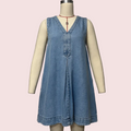 A sleeveless light blue denim dress displayed on a cream-colored mannequin torso against a plain light gray background. The dress has a V-neckline with button details down the front and a relaxed, flared silhouette.