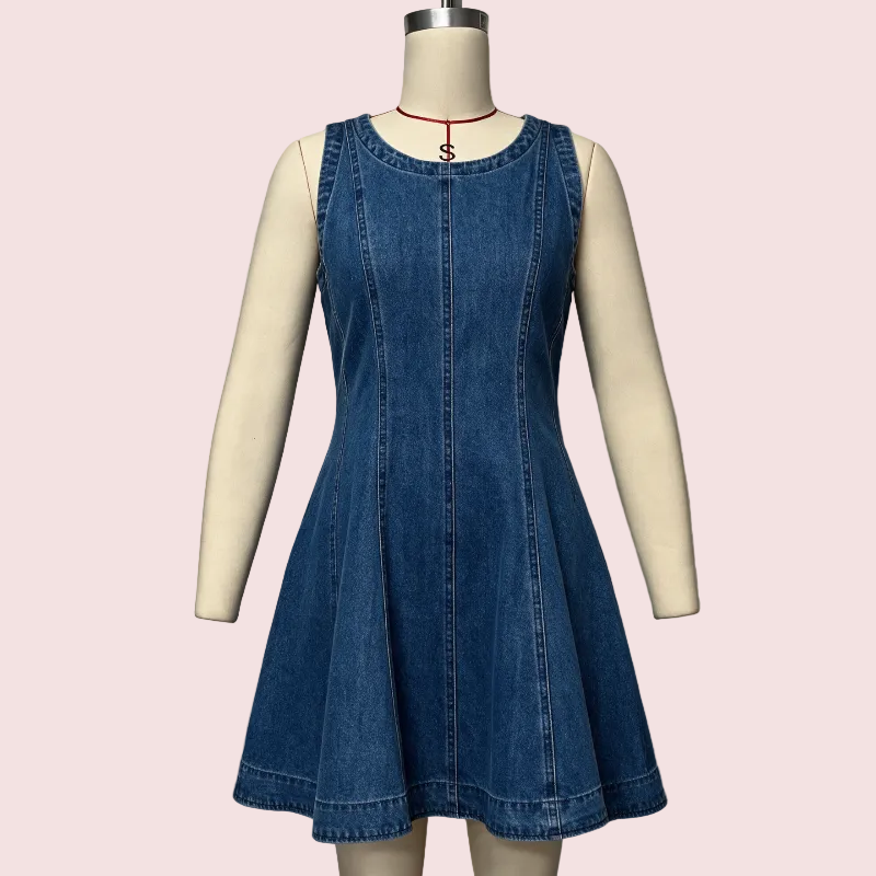 A sleeveless blue denim dress displayed on a cream mannequin against a pale pink background. The dress has a round neckline, a front center seam, and a flared skirt.