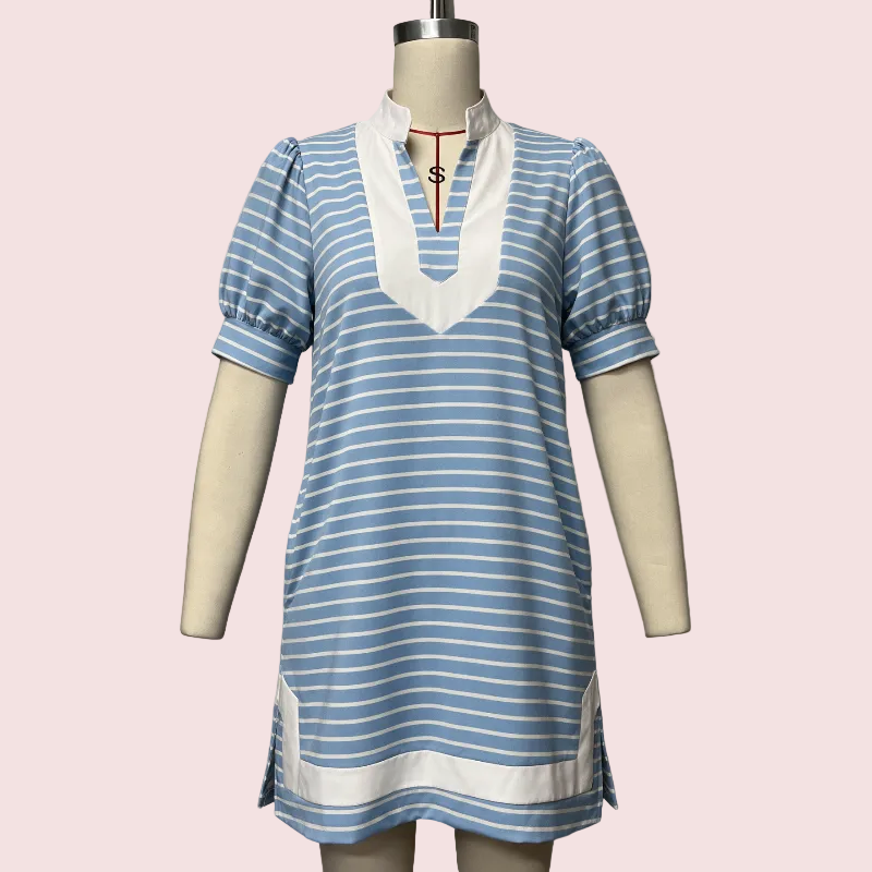 A short-sleeve tunic dress with light blue and white horizontal stripes, featuring a white V-neckline with a red drawstring detail, displayed on a cream-colored mannequin against a solid pale pink background.