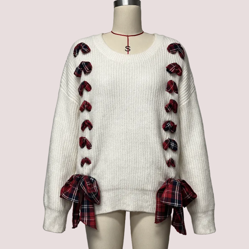 An off-white ribbed knit sweater displayed on a mannequin, featuring red and black plaid bow details down the front and tied at the cuffs.