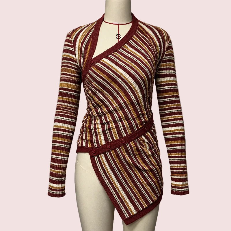 A long-sleeve wrap-style top displayed on a mannequin torso against a plain light gray wall. The garment has horizontal multicolor stripes with a deep burgundy base and warm tan, cream, and rust tones throughout.