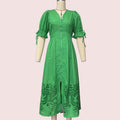 A bright green midi dress with puff sleeves, a front zipper, and eyelet embroidery near the hem, displayed on a cream mannequin against a plain white wall.