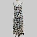 A sleeveless black maxi dress with a tiered ruffle skirt, featuring an all-over print of circular plates with colorful floral and decorative motifs. The dress is displayed on a mannequin against a plain white backdrop.