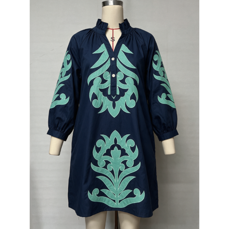A navy blue long-sleeve tunic dress with mint green baroque-style embroidery, displayed on a mannequin against a light gray background.