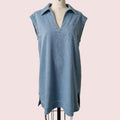 A light blue sleeveless collared shirt dress displayed on a cream dress form mannequin against a neutral beige wall.