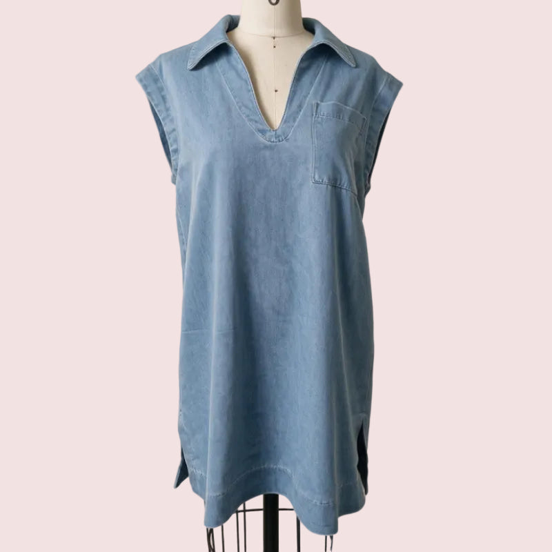 A light blue sleeveless collared shirt dress displayed on a cream dress form mannequin against a neutral beige wall.