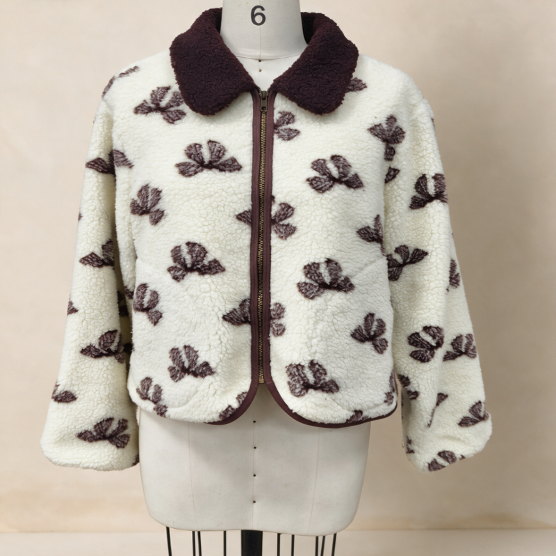 A cream-colored sherpa fleece jacket with a dark brown patterned leaf design and a dark brown collar, displayed on a white dress form mannequin.