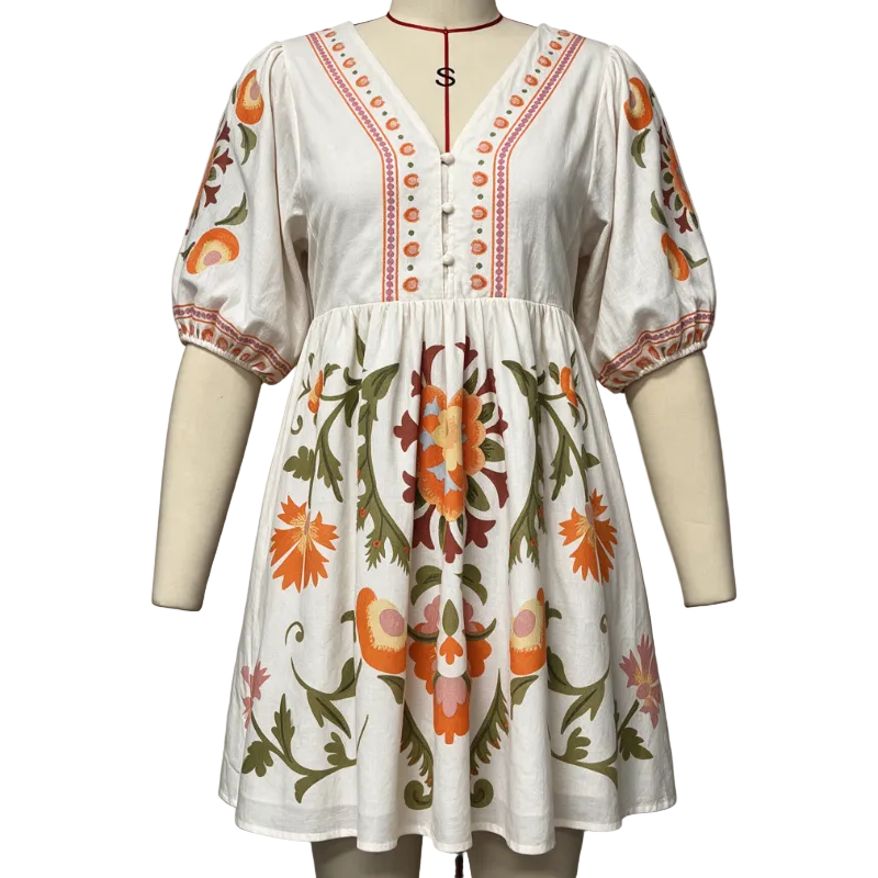 A white short-sleeve dress with colorful floral and bird embroidery, displayed on a mannequin against a plain gray background.
